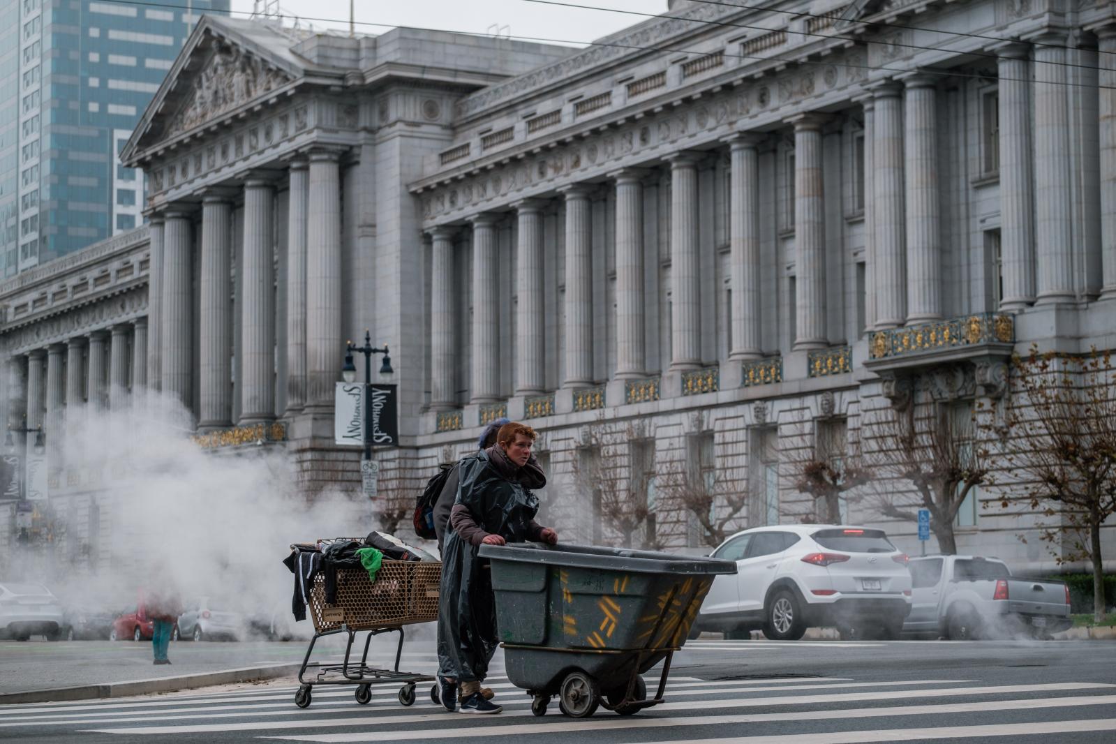 Image from NEWS FEATURES - Homeless folks cross the street with their belongings...