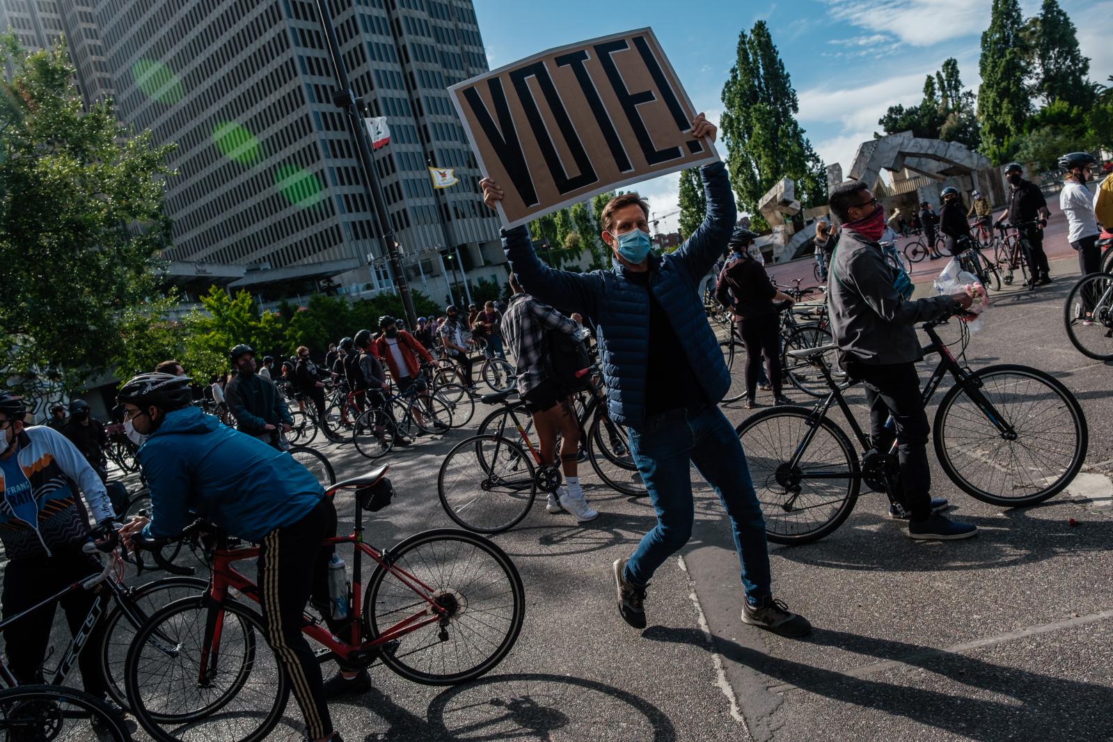 A man holds a &ldquo;Vote&rdquo; sign before the start of a Critical Mass style solidarity ride to demand an end to police violence in San Francisco on Friday, June 5, 2020.