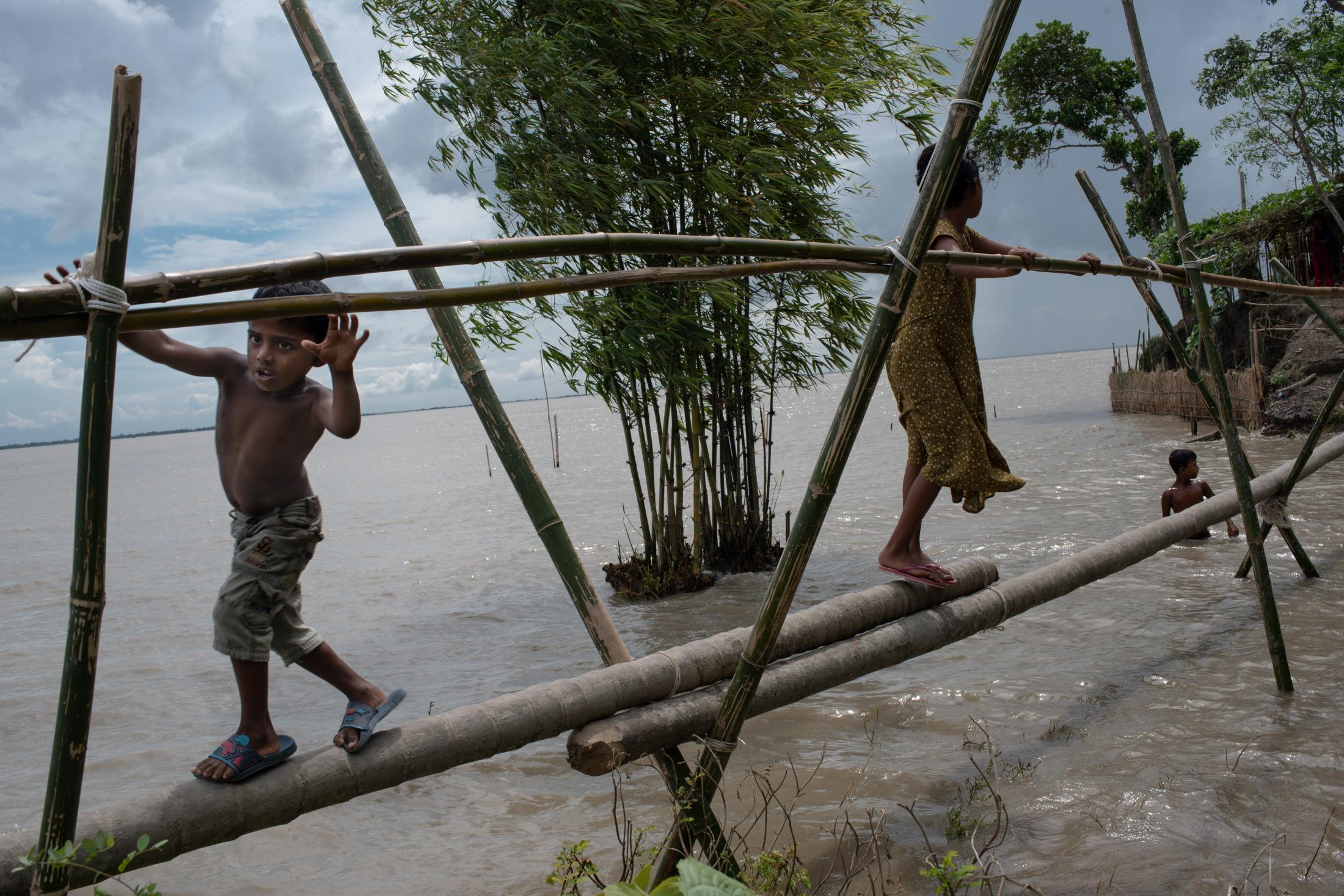 The Depth of Flood - Children cross the pool over a recently formed canal due...