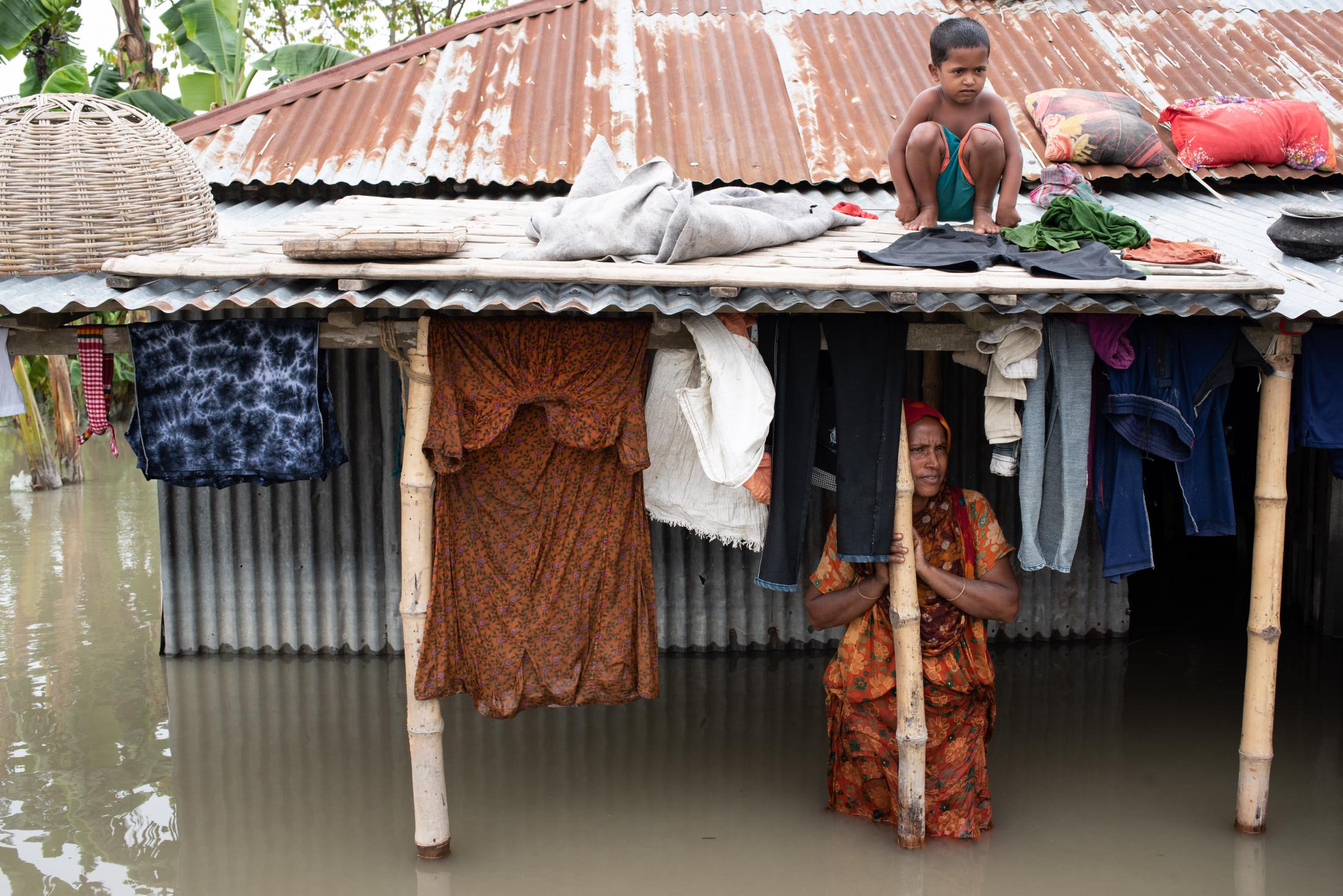 The Depth of Flood - A flood-affected woman stands in the water and a girl...