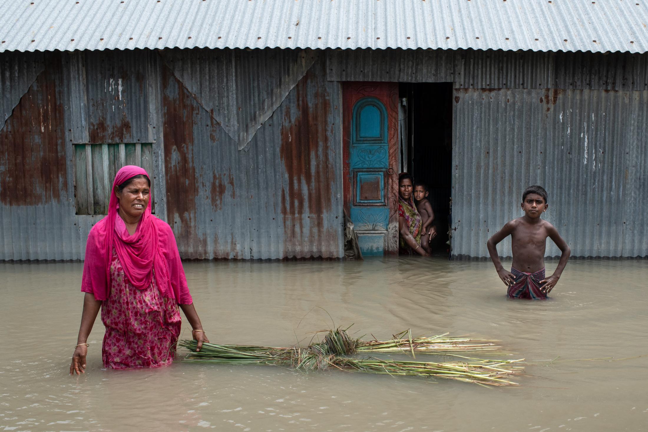The Depth of Flood - A flood-affected family stands in the water as their...