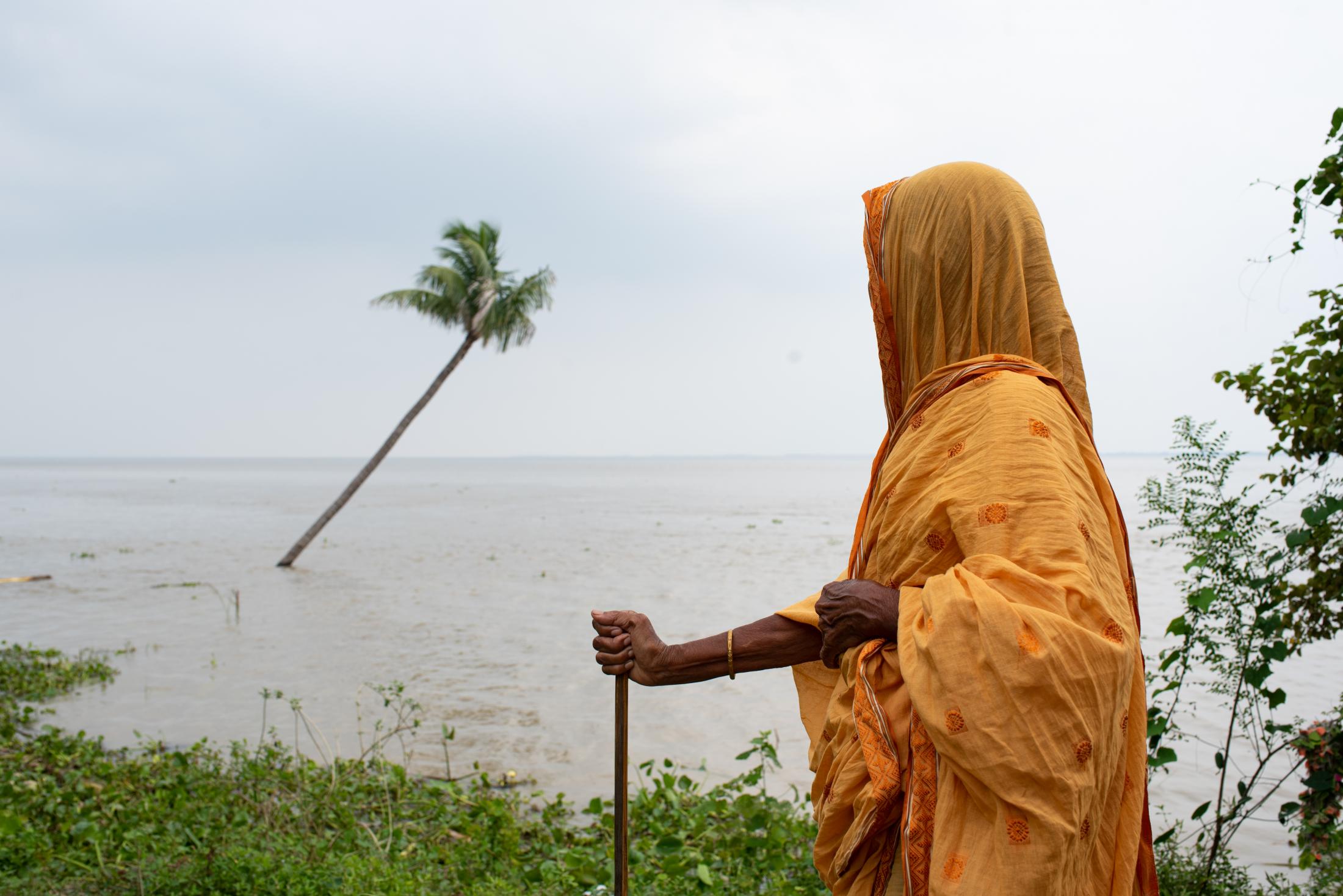 The Depth of Flood - Halima (80) stands in front of a flooded area where their...