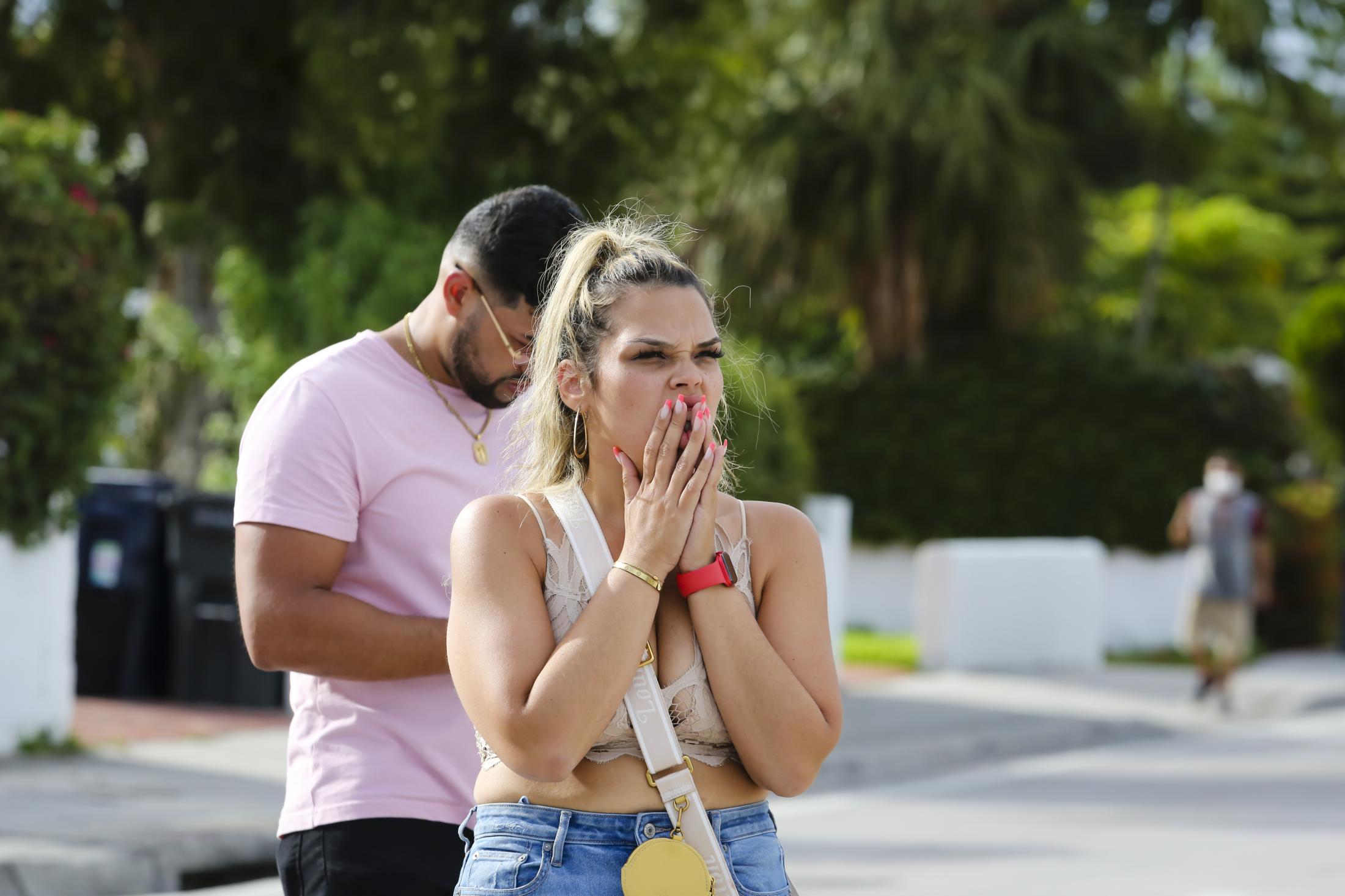 2021 - Surfside building collapsed - A woman reacts as she sees a partially collapsed building...