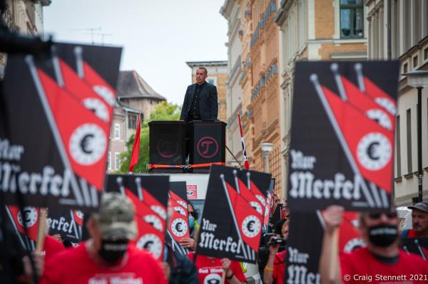 HALLE, GERMANY - OCTOBER 3: Elements of the &#39;Querdenken&#39; movement, &#39;Anti-Antifa Germany&#39; and other far right supporters and conspiracy theorists join together to demonstrate and march. The event held on The Day of German Unity was organised by Sven Liebich-seen leading the demonstration from a podium aboard a lorry- in Halle (Saale). Outgoing German Chancellor Angela Merkel attends celebrations to mark Unity Day on October 3, 2021 in Halle, Germany. Unity Day marks the reunification of Germany in 1990 following its division between West Germany and East Germany during the Cold War. (Photo by Craig Stennett/Getty Images)