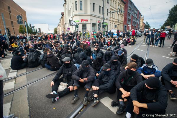 HALLE, GERMANY - OCTOBER 3: Protesters block a street in the city centre as part of a counter demonstration held by &#39;Halle against the Right&#39; against supporters of the &#39;Querdenken&#39; movement and members of the far-right who were marching and protesting against Angela Merkel, under the loose and contradictory title of &#39;Geil Merkel,&#39; on German Unity Day on October 3, 2021 in Halle, Germany. Merkel is in Halle today to attend Unity Day celebrations. Unity Day marks the reunification of Germany in 1990 following its division between West Germany and East Germany during the Cold War. (Photo by Craig Stennett/Getty Images)