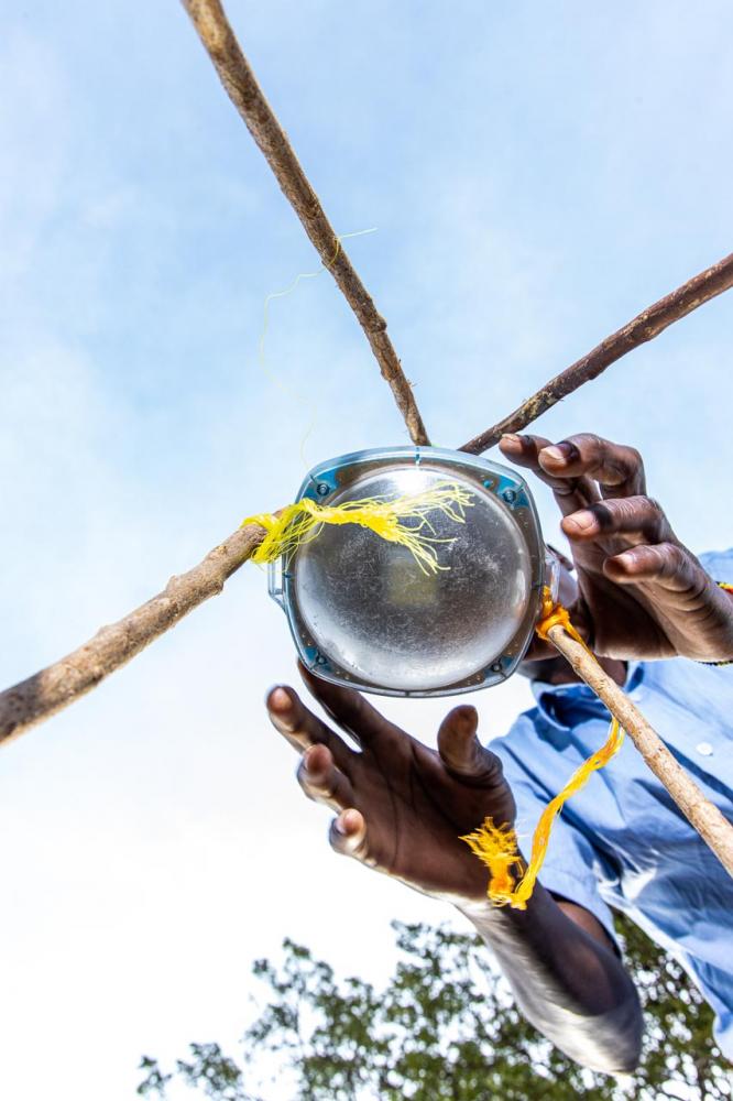 A solar lamp being fixed by Odongo Eric at the lakeshore on Rusinga Island. The fishermen make the stands using a light tree branch. Each squad of fishermen will handle about 10 light stands each night.