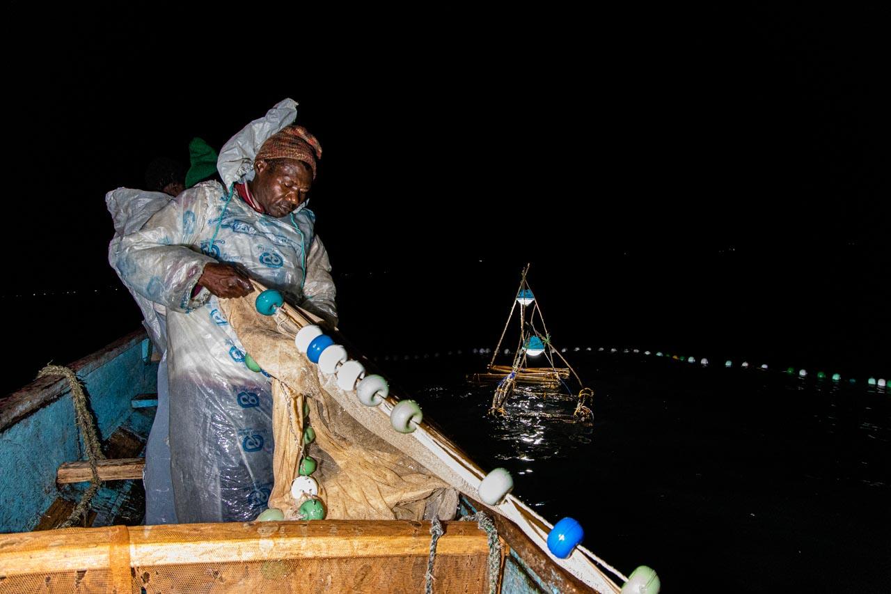 At around 11 p.m., Otieno Ngare retrieves his casted net out from the lake containing some silver fish. He will revisit the lamps every hour to check for fish.