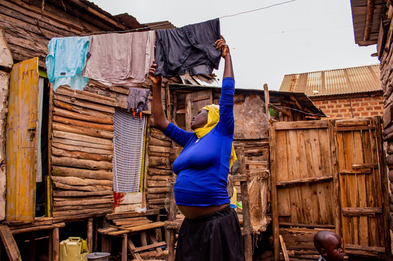 An expectant mother in the suburbs of Kalerwe hangs freshly-washed laundry to dry.