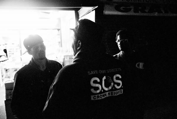 S.O.S outreach team member talking to young adults, during one of his night walks in the neighborhood of Crown Heights.