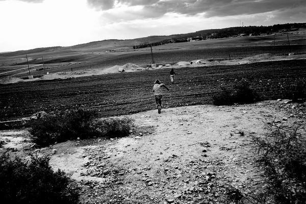 A Palestinian kid, running towards what used to be the 1967 border line between Israel and Jordan (now West Bank), in order to cross into Israel. South Mt Hebron, West Bank.