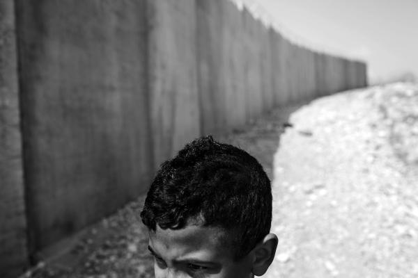 A Child from Ar Ramadin tribe playing alongside the new separation barrier wall that was built right in front of his family house. Ar Ramadan village, South Mt. Hebron. West Bank.