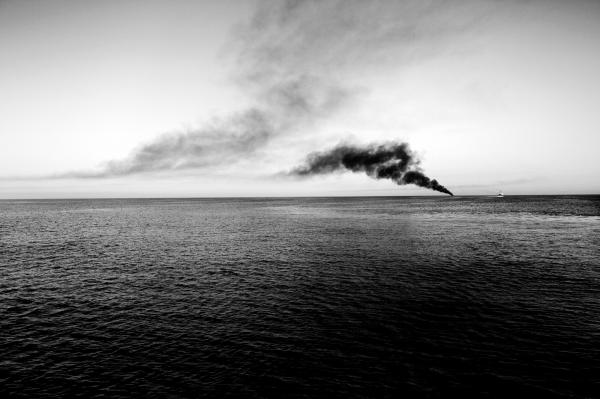 Image from On Strange Waters - Smoke rises from burnt rubber boats. the Italian navy...