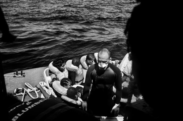 Image from On Strange Waters - An Italian navy officer waiting to pick up more refuges...
