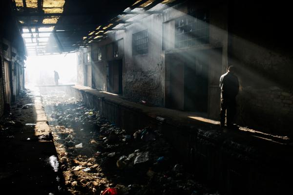 Refugees standing between two abandoned warehouses, where they sleep in, at the back side of Belgrade train station.