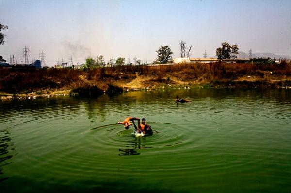 Children playing in a water dump at the village of Sarayplay, which borders the main steel plant in Raigrah city, Chhatisgrah, India.