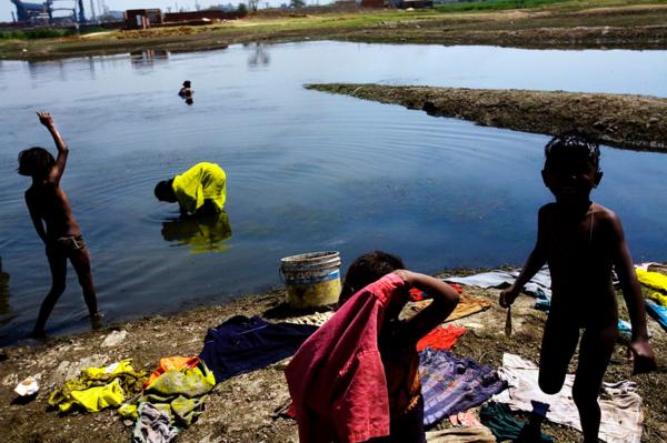 Globalisation - Industrialisation - Children searching for fish, near the main steel plant,...