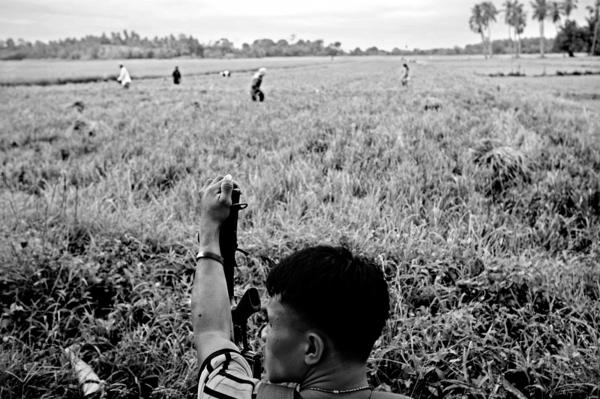 Rodel Cantomayor (c) guarding his fellow family members while they work in the fields located at the no mans land area between christian and muslim communities.