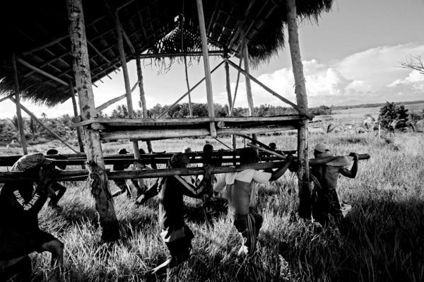 Ilaga members moving a deserted muslim shack near their fields, at the no mans land area between christian and muslim communities.