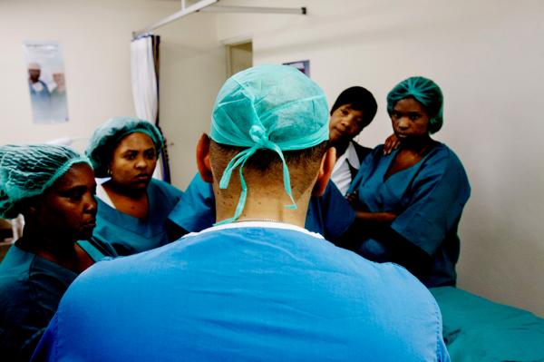 An international team member, talks to local medical staff in the clinic, before the beginning of a circumcision procedure.