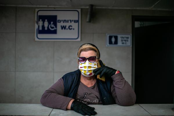A woman talking over the phone, while keeping a public urinal clean. at the vegetable market, in the city of Beer Sheva.