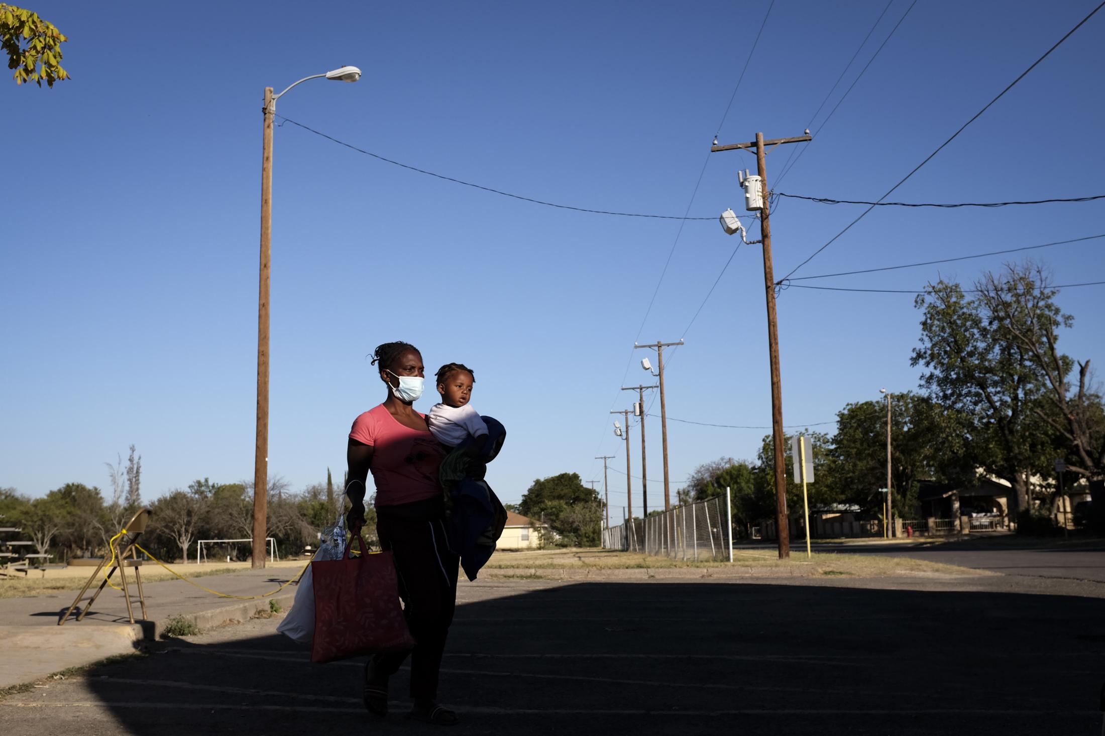 U.S. removes asylum-seeking migrants from Texas border camp - Migrants seeking asylum in the U.S. walk towards a bus to...