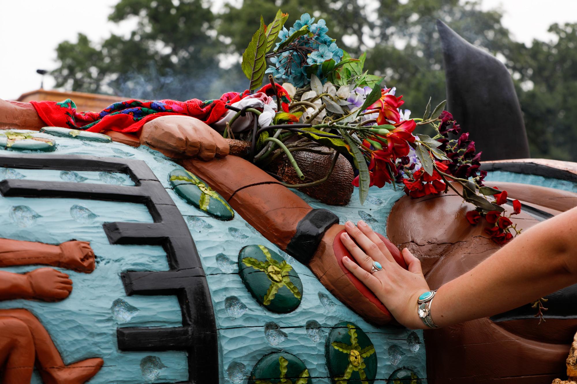 Woman places her hand over red carved hand on totem pole in the National Mall in Washington, DC. Thursday, July 29, 2021.
