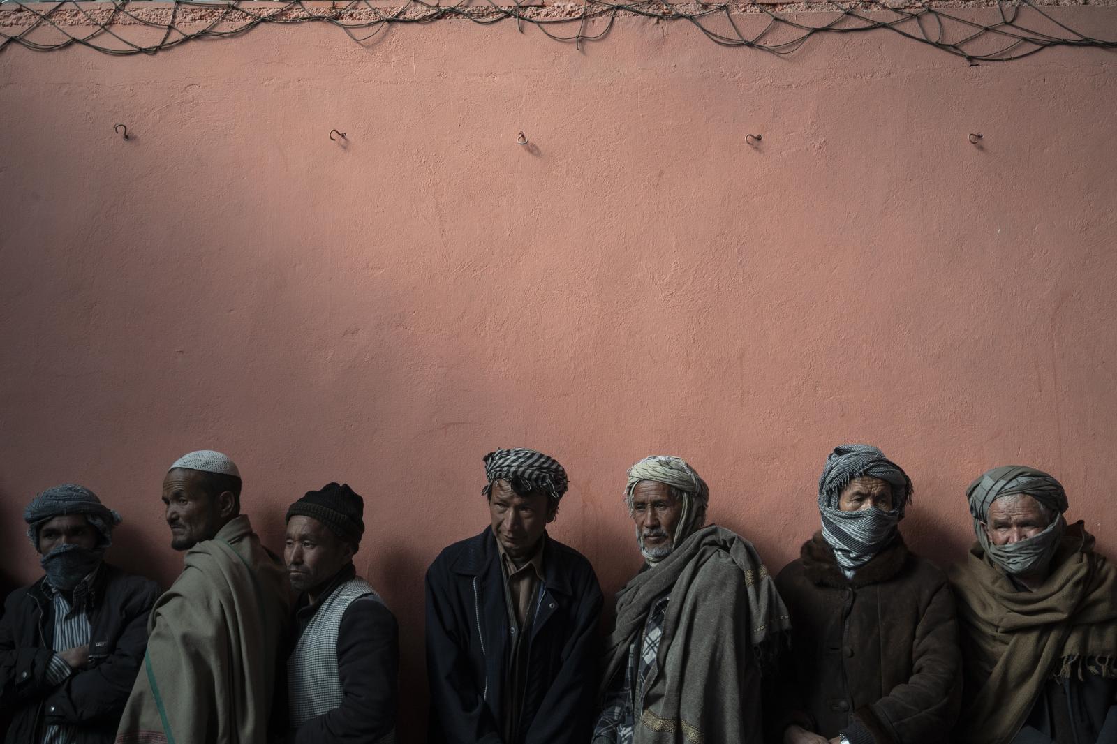 Image from SINGLES - Men wait in a queue to receive cash at a money...