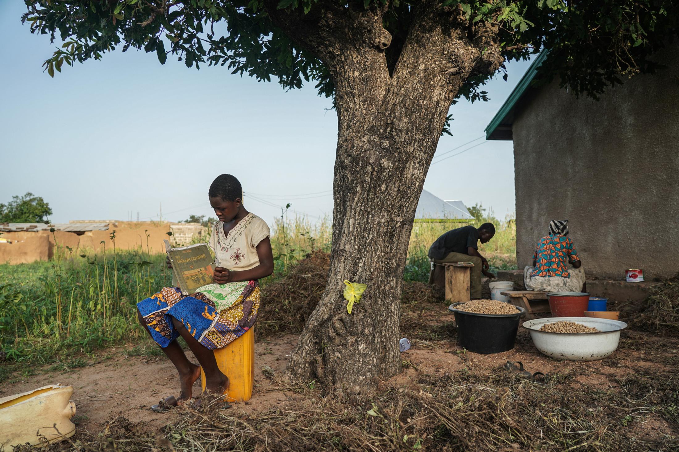 Tales Under the Baobab Tree - Florence Azudaa (13) reads after school outside her...