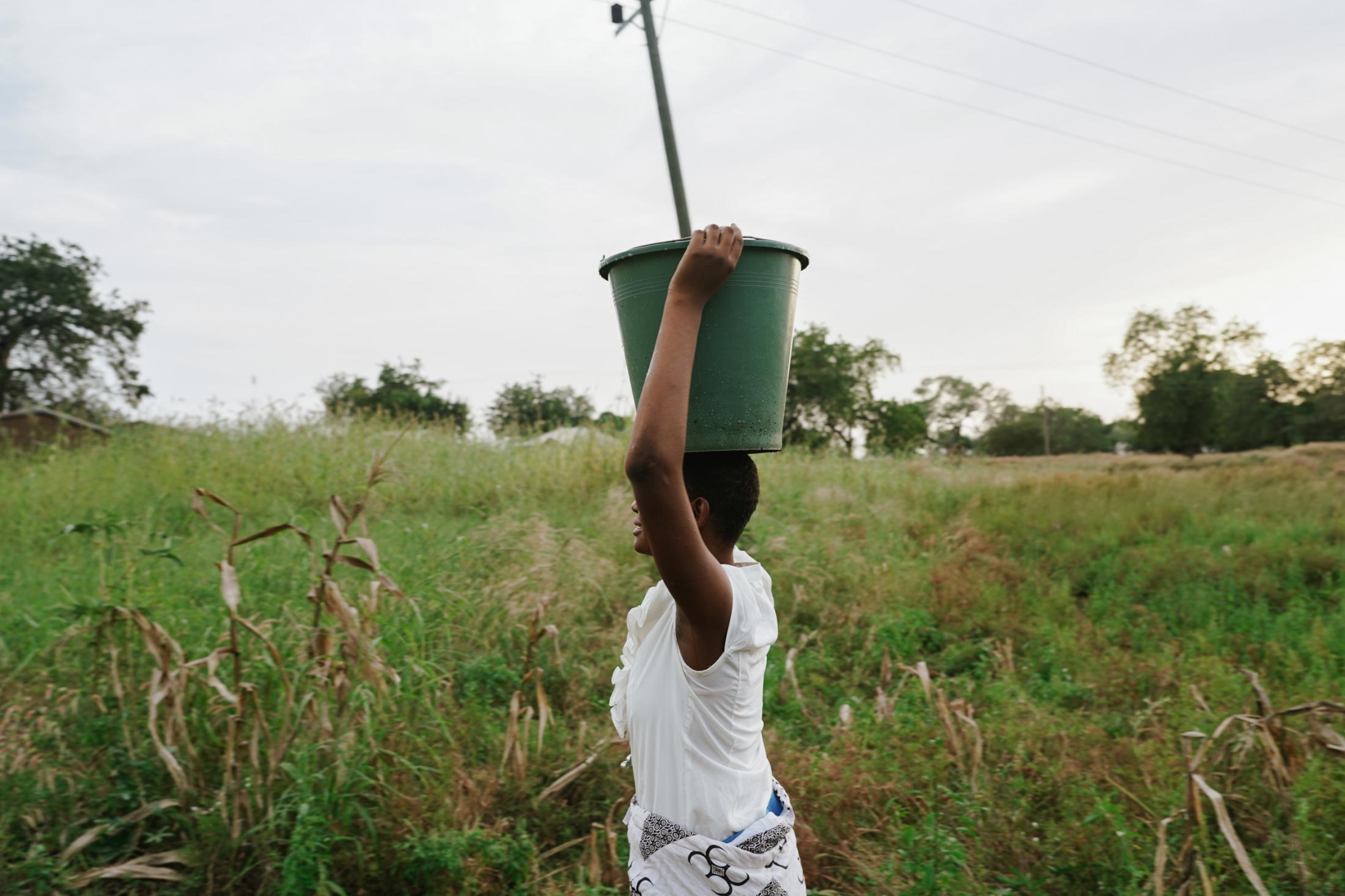 Francisca Akanko (14), student of Azenab Girls Primary School, fetches water as one of her after school chores. Wiaga, Upper East Region of Ghana,...