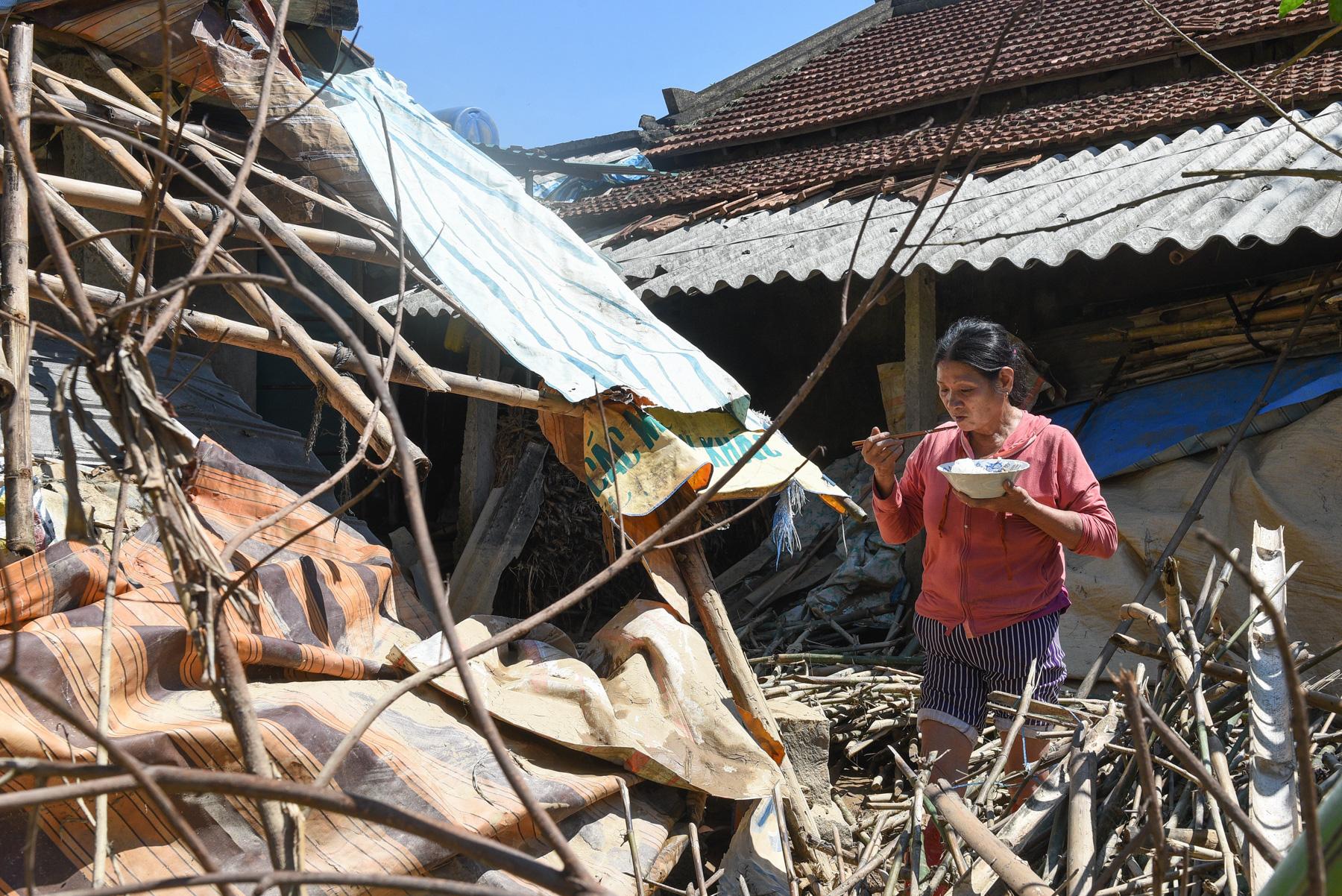 A month with full of sorrow - A woman eats next to her house damaged by the Typhoon...