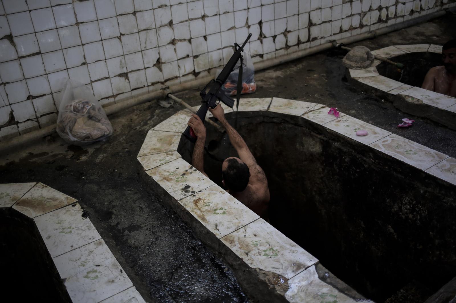 A federal police officer puts his machine gun on the edge of the bath in the Hamam Alil spa. The spa reopened several months ago after the town was liberate from the Islamic State group. Many Iraqi soldiers visit the spa, located half an hour south of Mosul, in between fighting against the Islamic State group for relaxation.&nbsp;