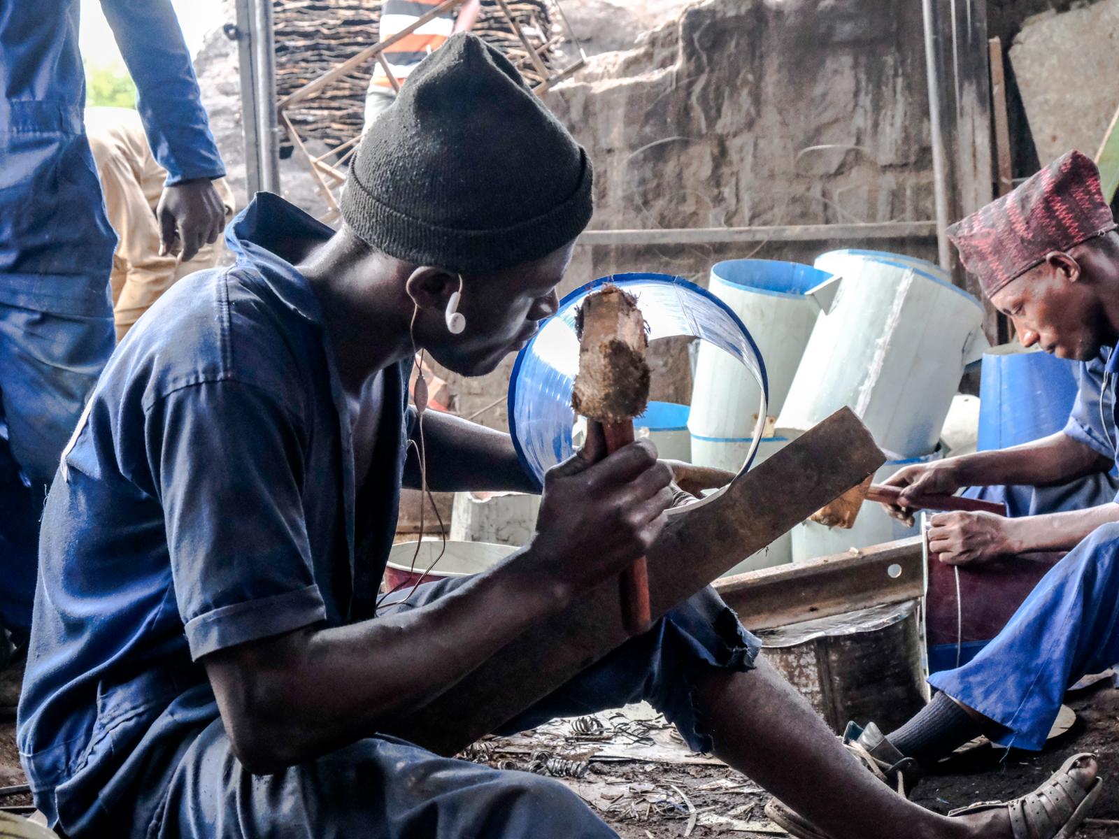 Bending with a wooden hammer th...water tanks. Kigali, March 2020