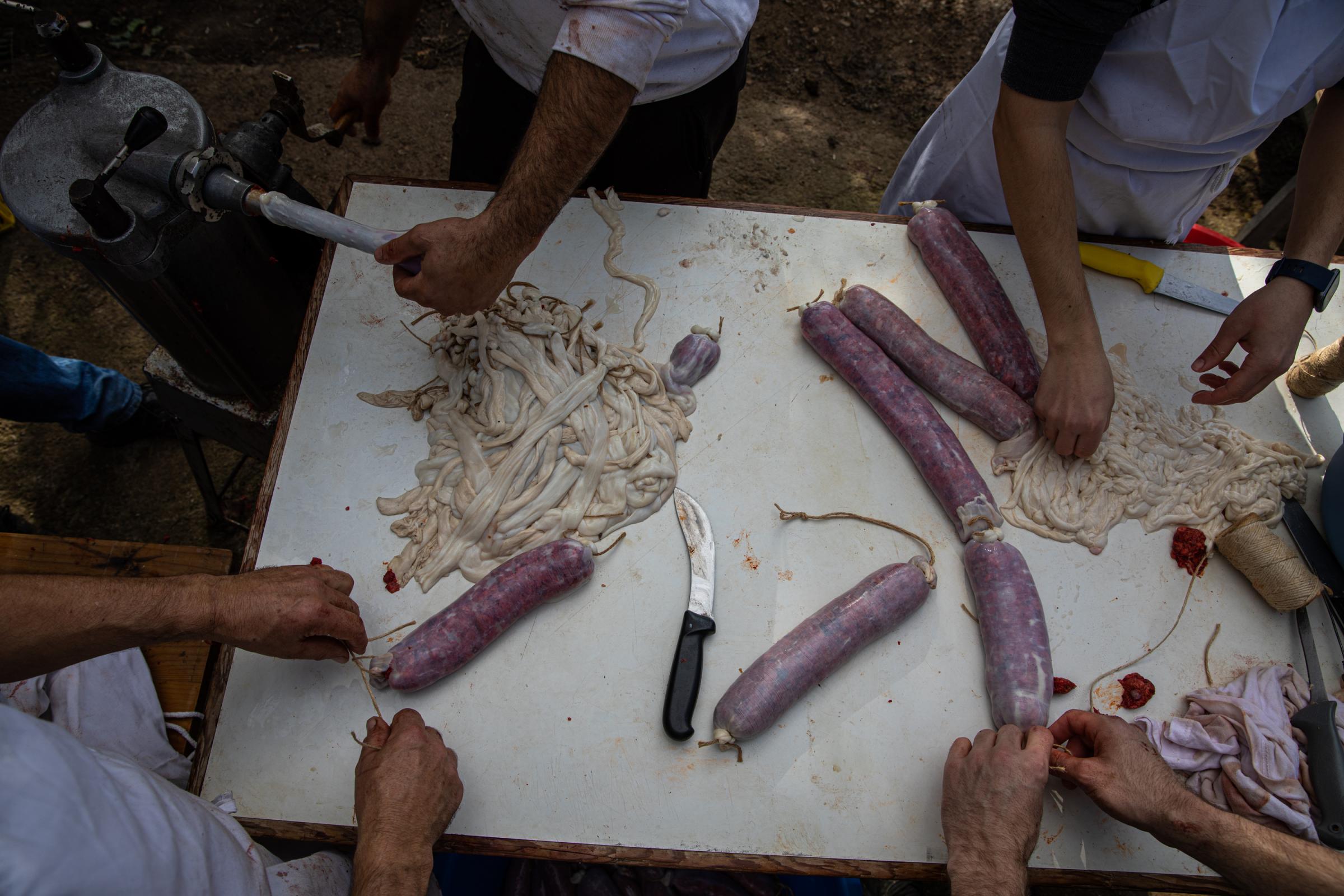 Spain's Sustainable Swine Slaughtering For Prized Iberian  - IBIZA, SPAIN - DECEMBER 06: Men prepare sausages with the...