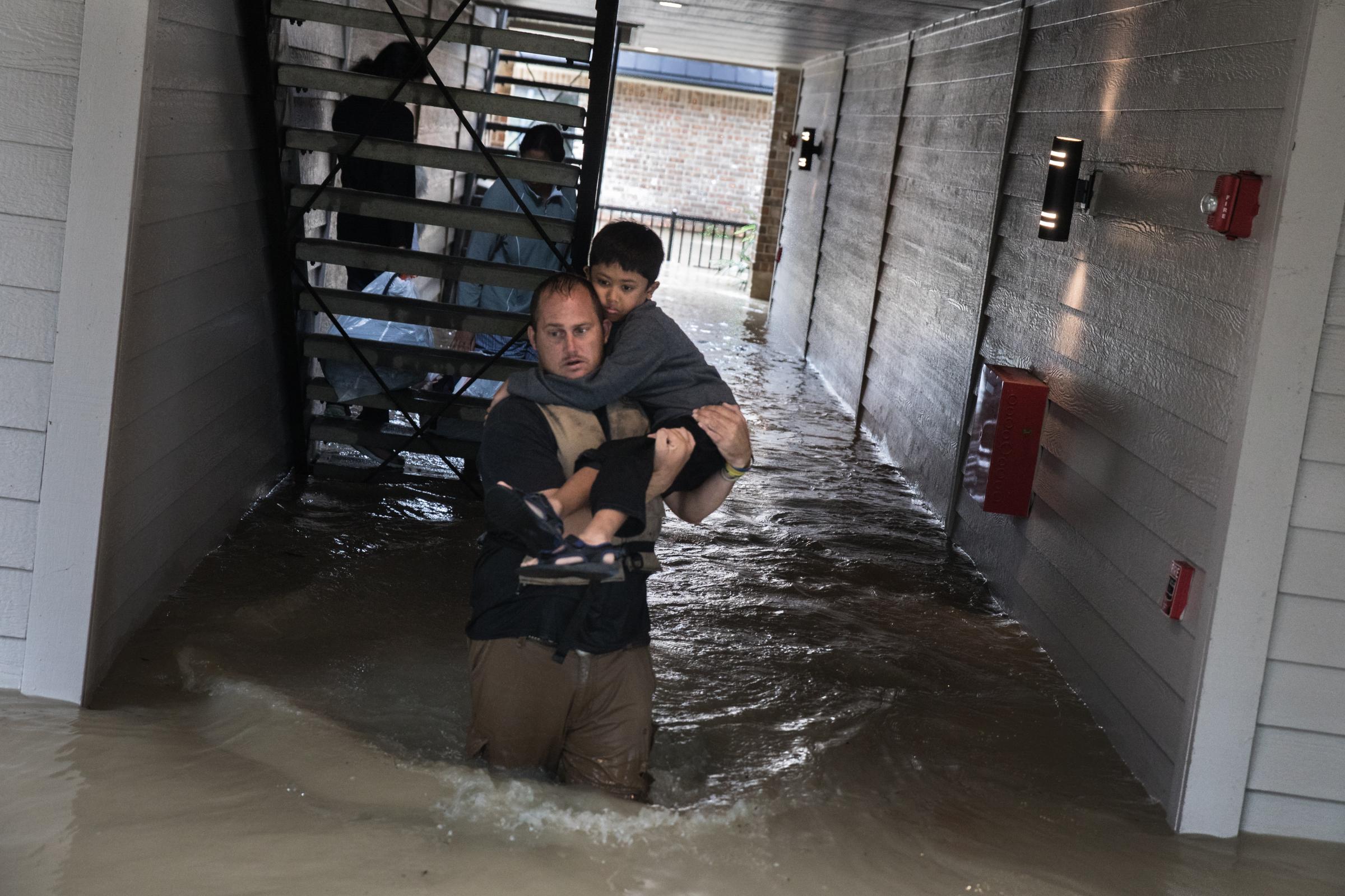 Dustin Langley helps evacuate a family from their flooded apartment in Kingwood, Texas