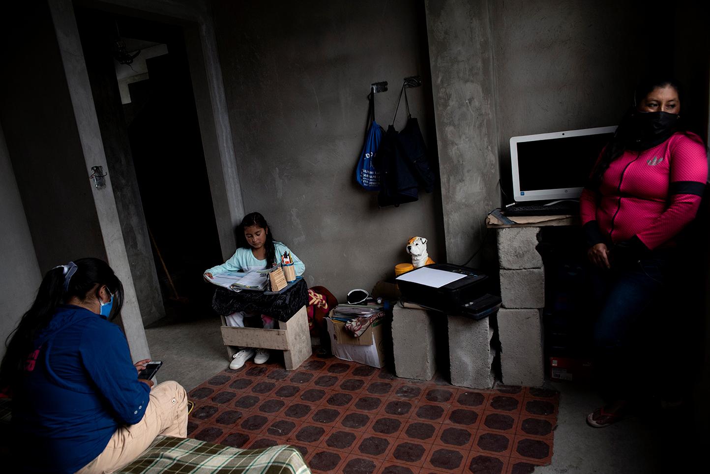 Anah&iacute; Cadena, 11 years old, does her homework at home with the company of her mothers...