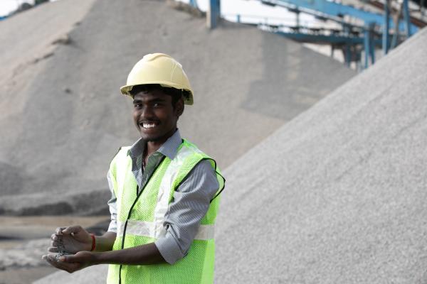 KANCHIPURAM, INDIA (12/20/2021) - Portrait of Ramkumar, PCS Plant Operator showing the quality of VSI 06 stones at PCS Industries located at Periya Venmani, Kanchipuram, Tamil Nadu, India PCS makes manufactured sand, M-Sand which is more sustainable and cost effective in comparison to ordinary river sand. M-Sand is sand produced by crushing rocks, quarry stones or larger aggregates pieces into sand-sized particles by using State of the art machinery / plant by PCS. The organisation manufactures and distributes the M-Sand after a rigorous quality testing. PCS also strives to do the market research and testing for new concrete products for the low-income housing market. 