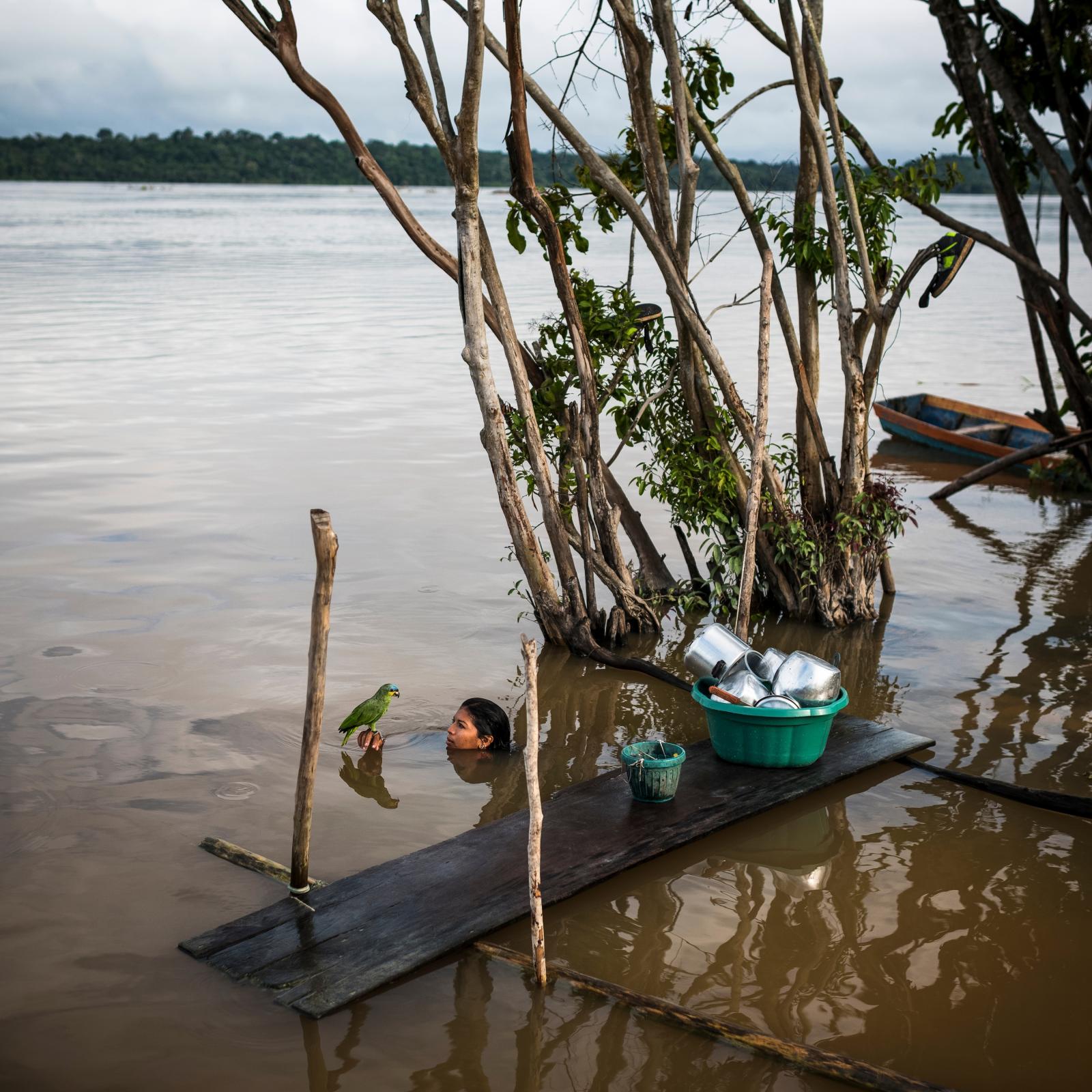 Lucicleide Kurap of the Munduruku village of Dace Watpu has a moment with a pet parakeet after washing dishes in the Tapajos River in Para State, Brazil. 2016 