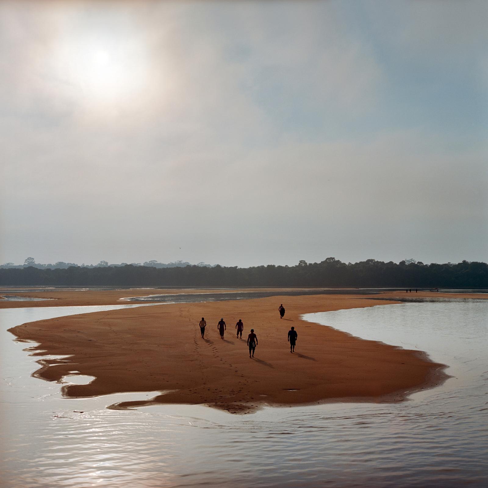 Members of the Munduruku indigenous tribe walk on a sandbar on the Tapajos River as they prepare for a protest against plans to construct a series of hydroelectric dams on their river in Para State, Brazil. 2014.
