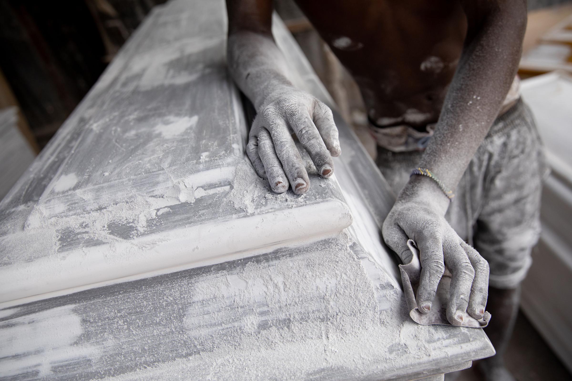 Covid Coverup - Mohammed Harris sandpapers a coffin before it gets painted in the Manzese district of Dar Es...