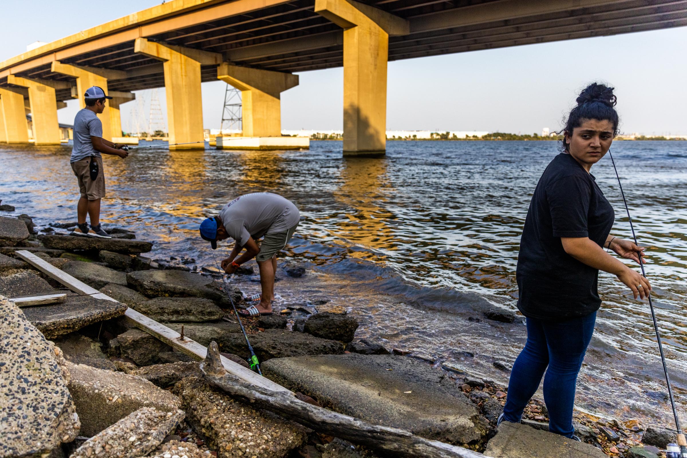 Erick Portillo, left, his father Angel Romero, center, and his sister Kayri Portillo fish in Bear Creek under the Francis Scott Key Bridge on July 16, 2021 at Fleming Park in Turner Station, Md. The family has lived in Turner Station for three years. &ldquo;This is something we like to do as a family,&rdquo; Kayri Portillo said. &ldquo;It&rsquo;s peaceful and quiet and really pretty.&rdquo;