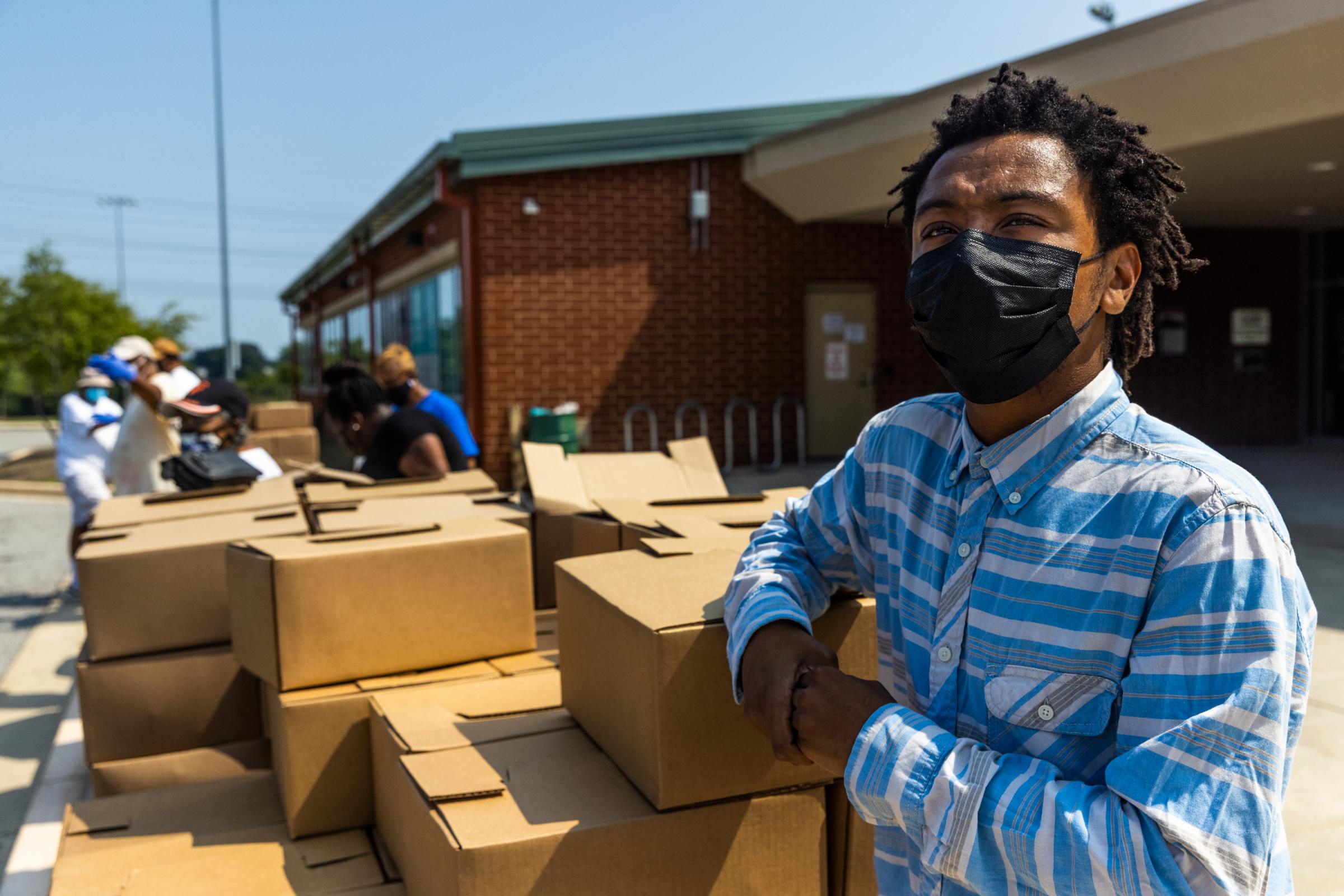 Turner Station: Heart and Soul - Devonte Wilkins stands next to boxes of food during...