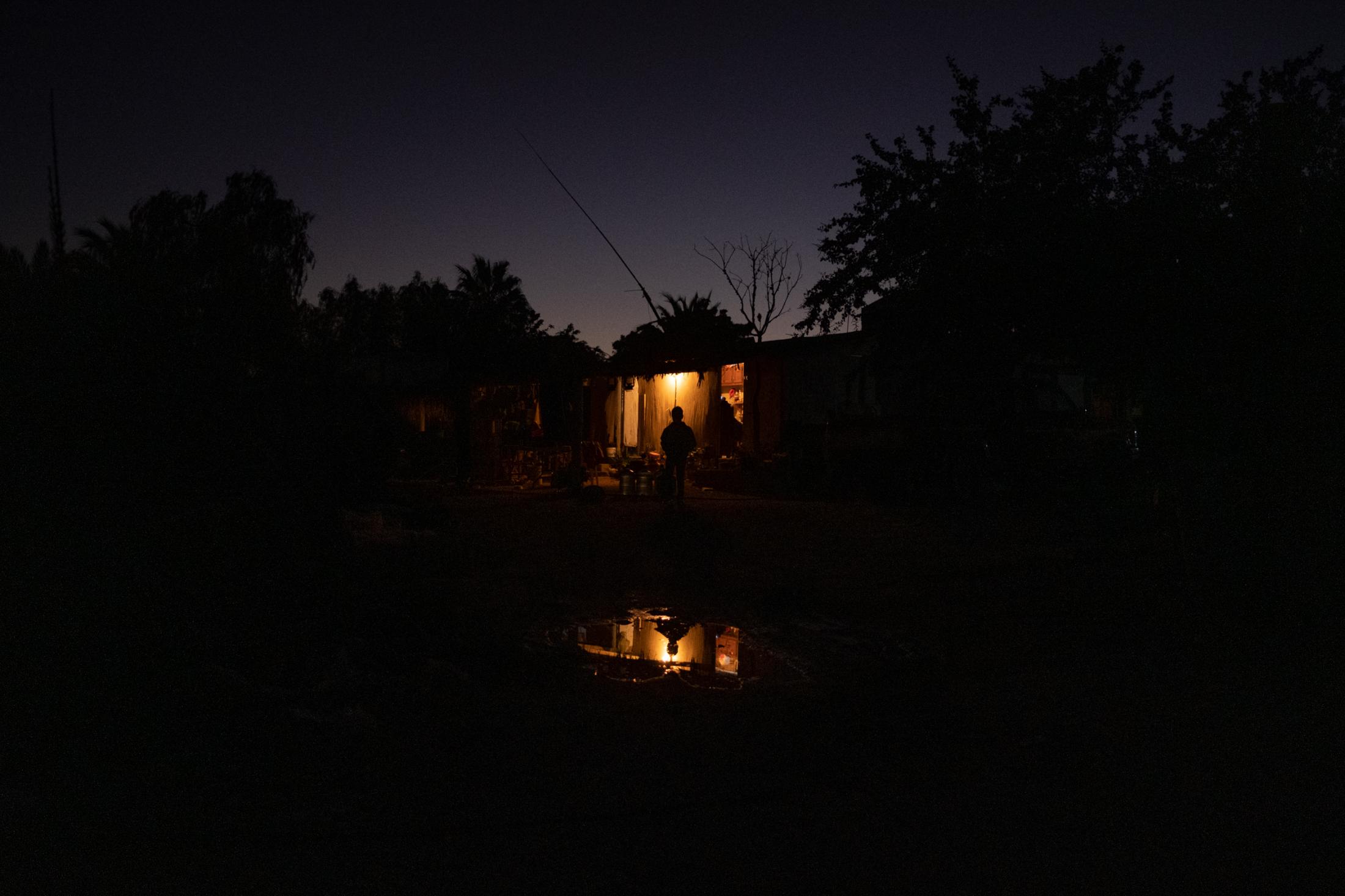 Until We Are Gone - Baja California -  Joan stands outside his neighbor's house at night in...