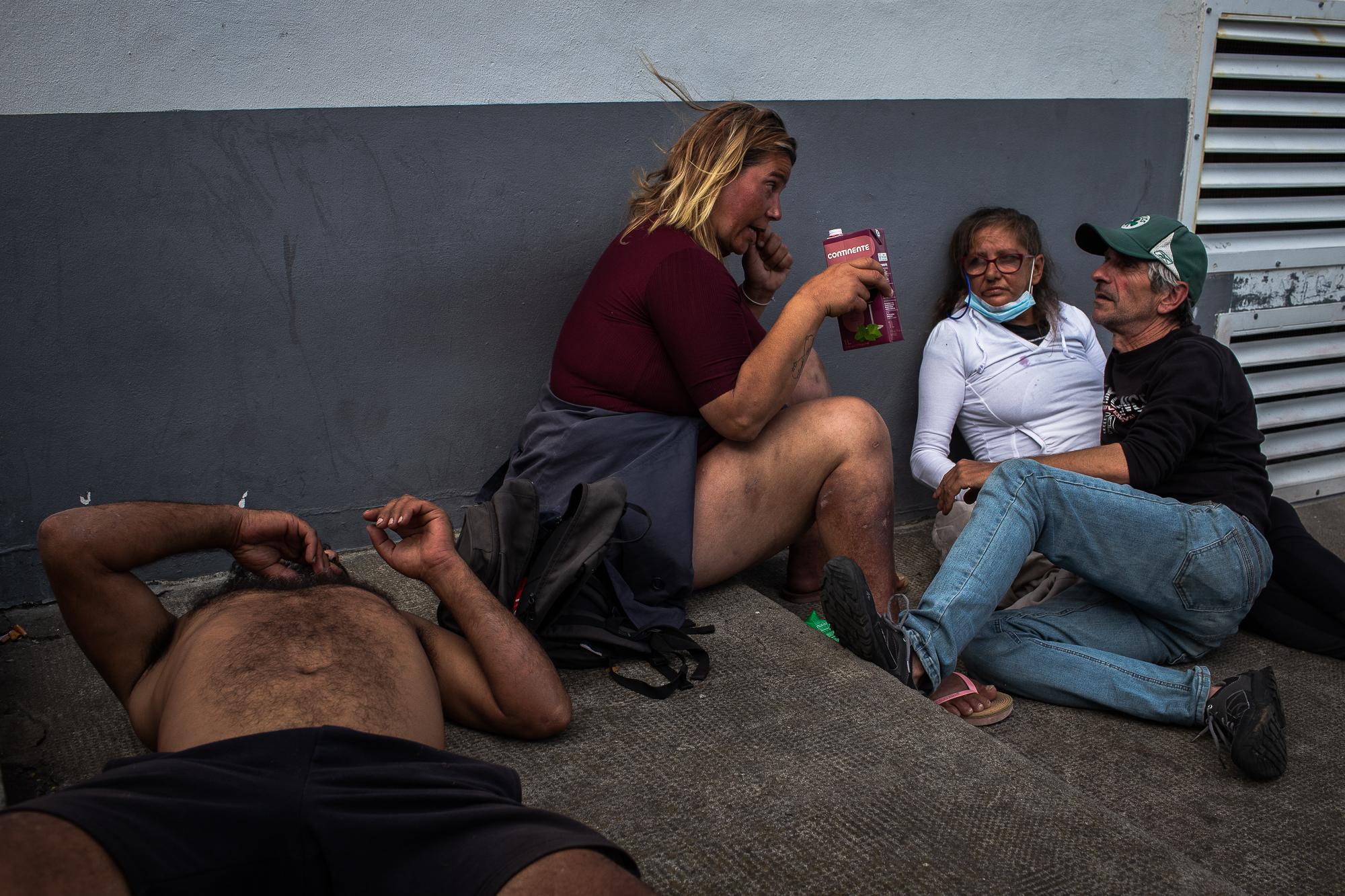 Evelina Bernardo (in white) hangs out with others repatriated in an alley where they spend days...