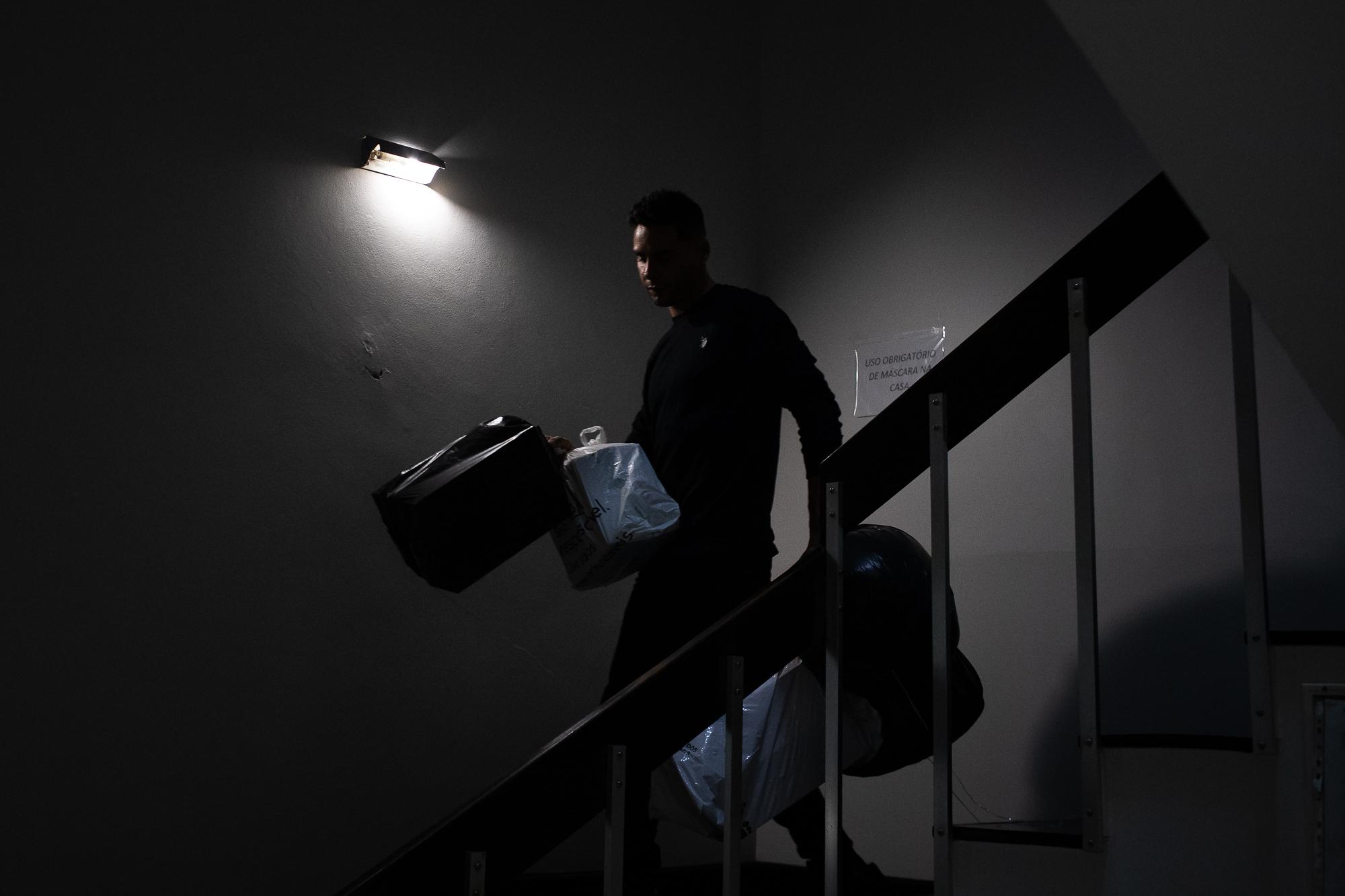 F&aacute;bio Medeiros walks down the stairs with his belongings while moving from the shelter...