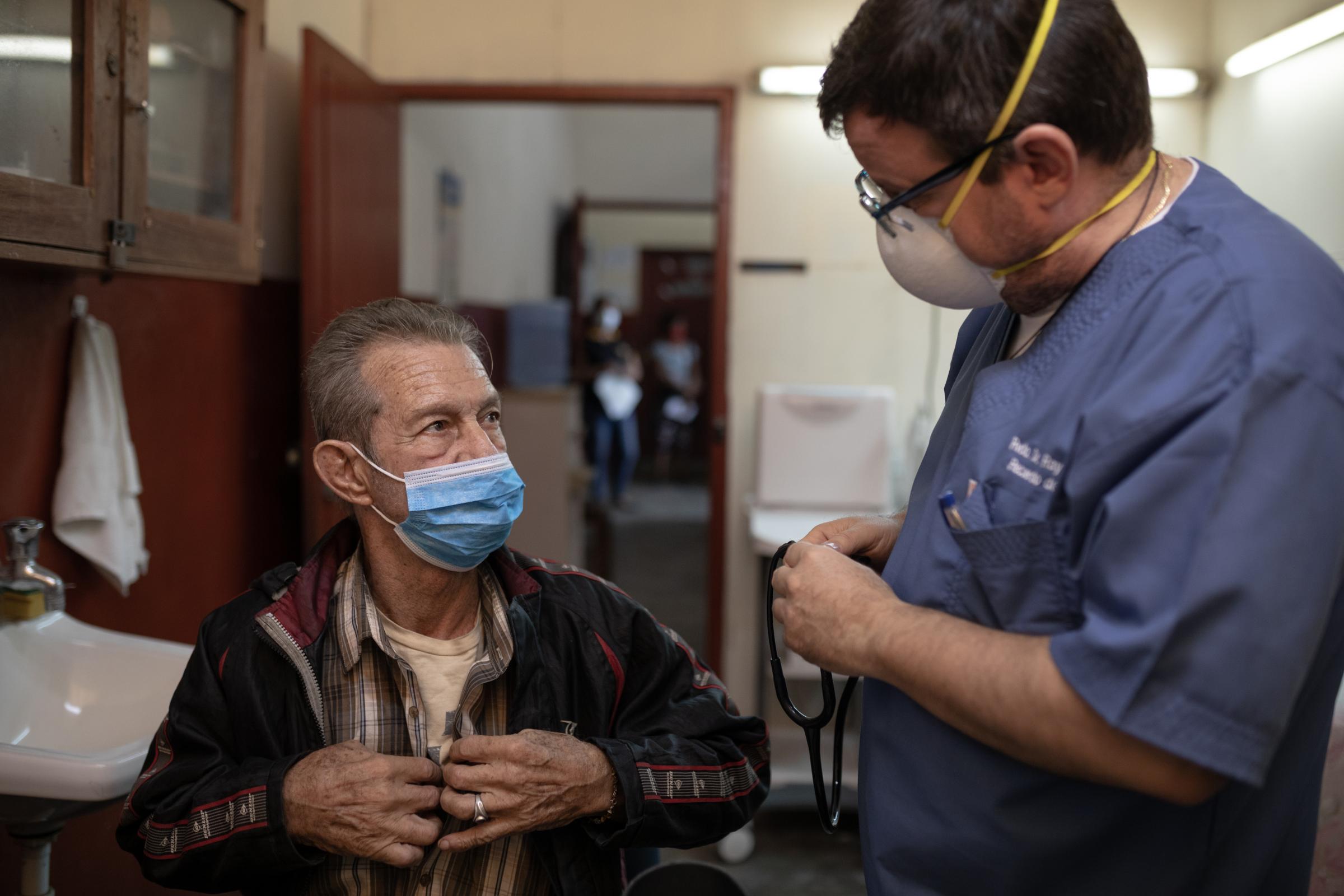 Vaccinators in Peru's Amazon are challenged by religion, rivers and a special tea - Raymond Portelli, priest and doctor treats a patient in his office located in the San Martin de...