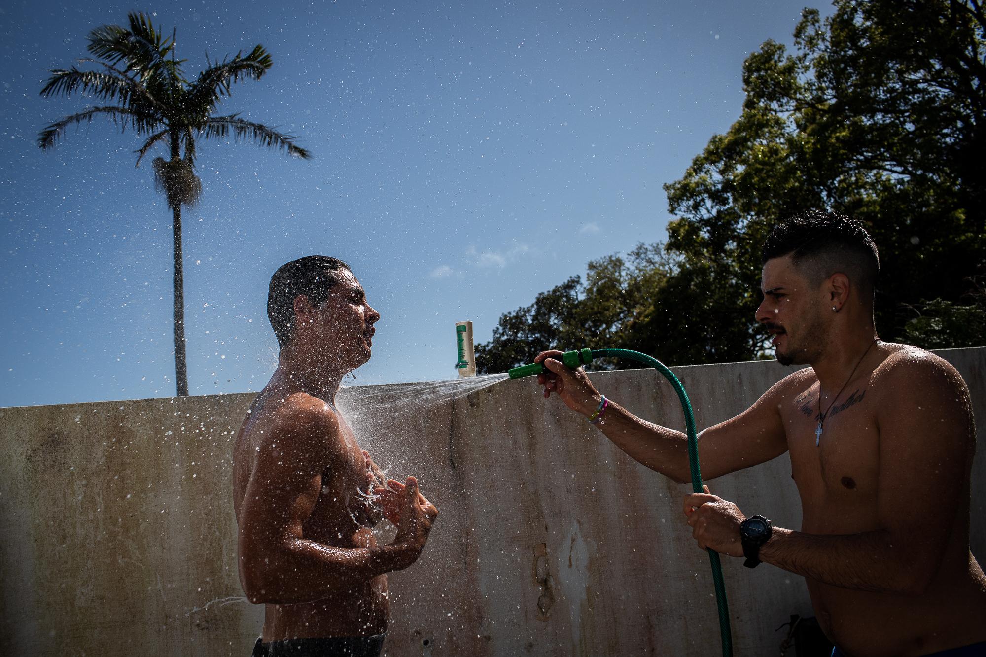 F&aacute;bio Medeiros gets hosed by a friend after exercising in the backyard of the shelter...