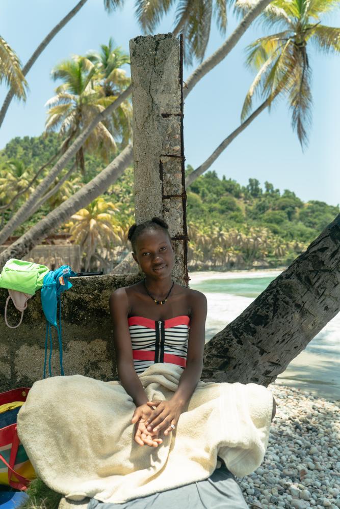 A young woman watches surfing f...ach in the afternoon in Jacmel.