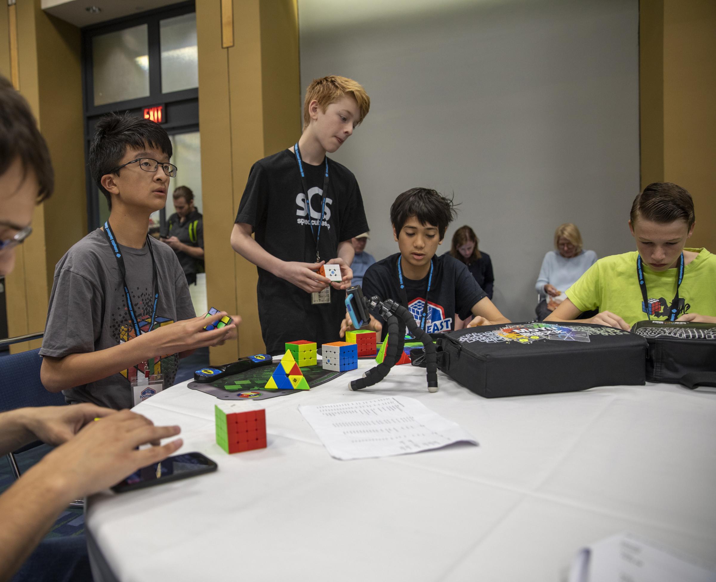 Speedcubers - When not competing, tables are filled with cubers talking algorithms, showing off cubes, and...