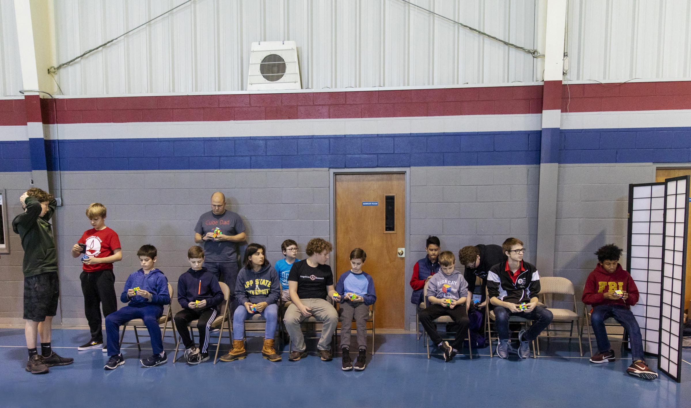 Speedcubers - Competitors wait &quot;on deck&quot; to be called to a table during a competition in...