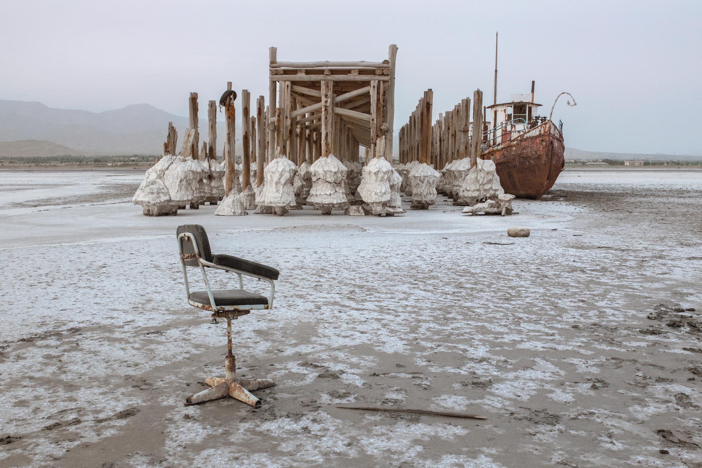  On the shore of Sharafkhaneh port in 2015, an abandoned ship sits wedged against a pier that leads nowhere. Sharafkhaneh port was once one of the most important ports on Lake Urmia. Ships used these piers to move people and equipment between cities around the lake. It has shut down, and few remaining ships have gone aground. 